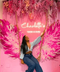 Neon wall setup with feather wings, florals and a swing for a cake and gift shop