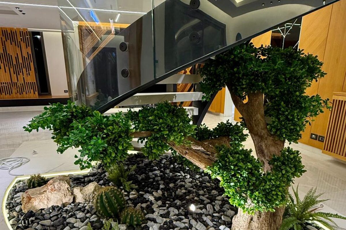 Artificial greenery bed and trees beneath a hotel staircase