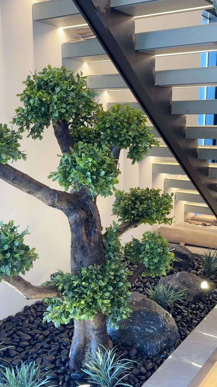 bonsai on black stones — home under a floating staircase, Lebanon — installation by Neon Jungle Studios