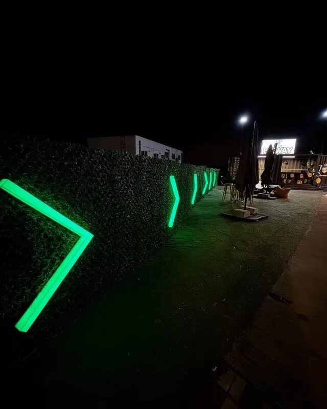 green neon arrows along a hedge — venue entrance, Lebanon — installation by Neon Jungle Studios