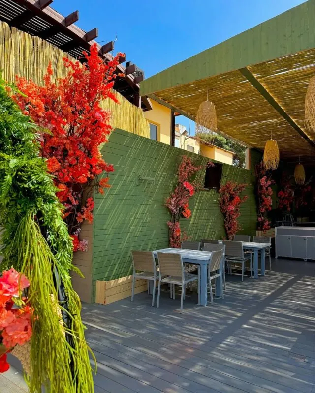 green walls and red blossom trees — seaside restaurant terrace, Lebanon — installation by Neon Jungle Studios