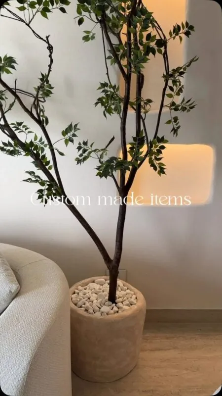 slim tree with airy leaves in a stone-look pot — living room corner, Lebanon — installation by Neon Jungle Studios